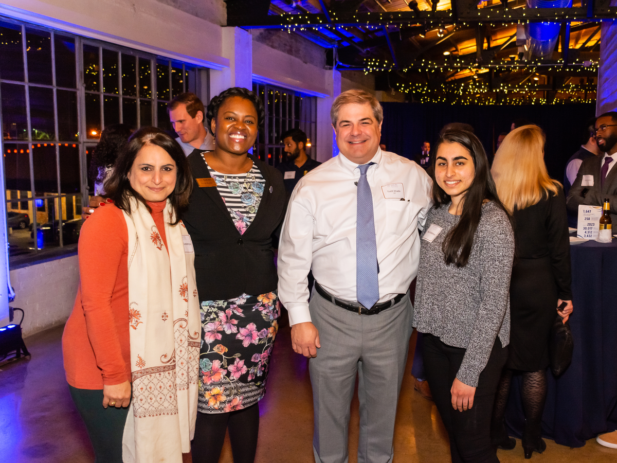 A group of three alumni—two women and a man—standing with the regional advancement staff person, Nicole Randle