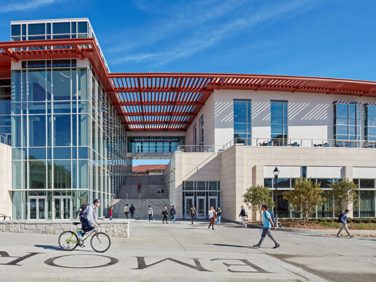 One entrance into the new Student Life Center (SLC) sitting against a blue sky. The SLC serves as a hub for student activity and features large windows, a light-colored facade, and a red roof.