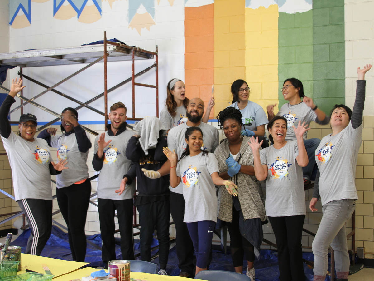 A group of alumni standing in front of a wall they were painting as part of Emory Cares.