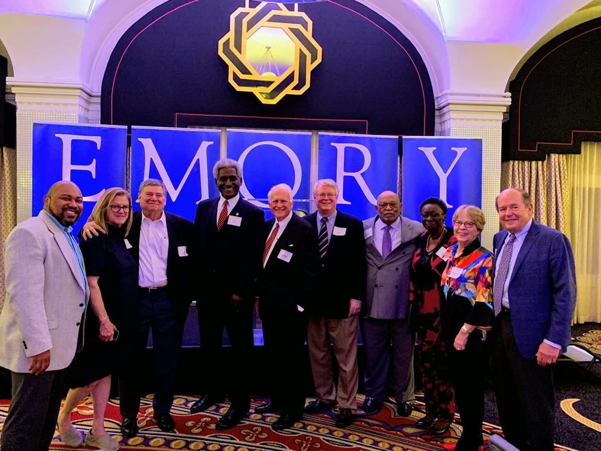 A group of alumni standing in front of banners spelling out EMORY.