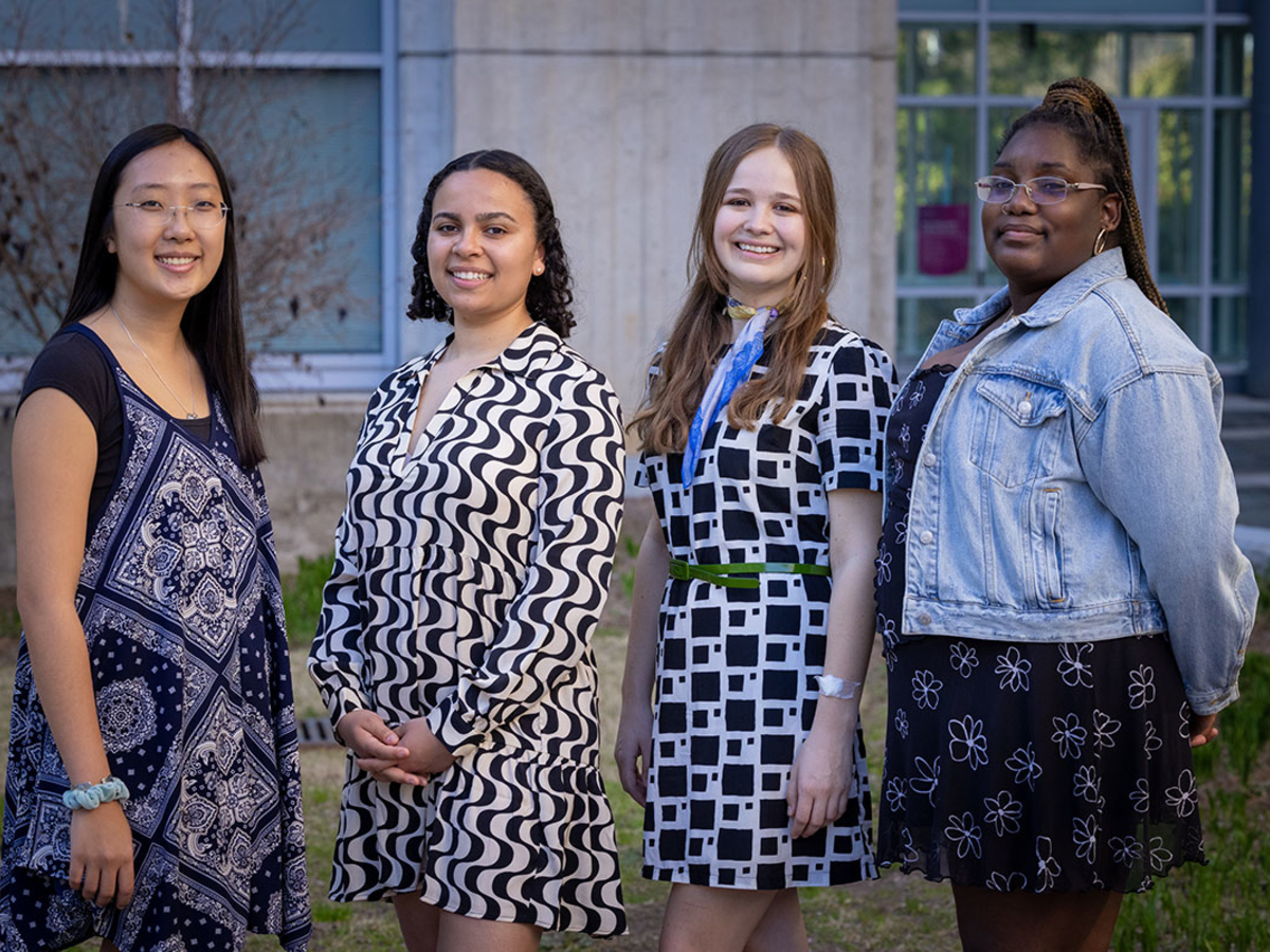 Four female students stand together and smiling at the camera.