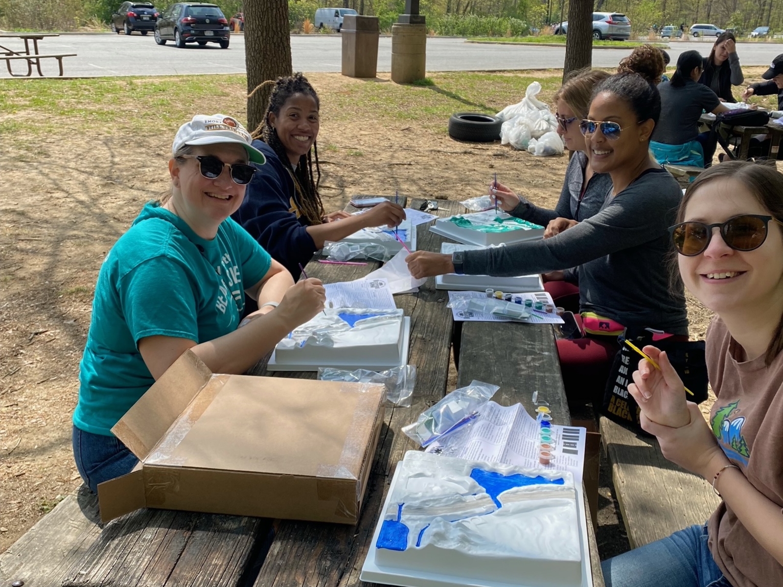 Group of people sitting at picnic table packing materials.