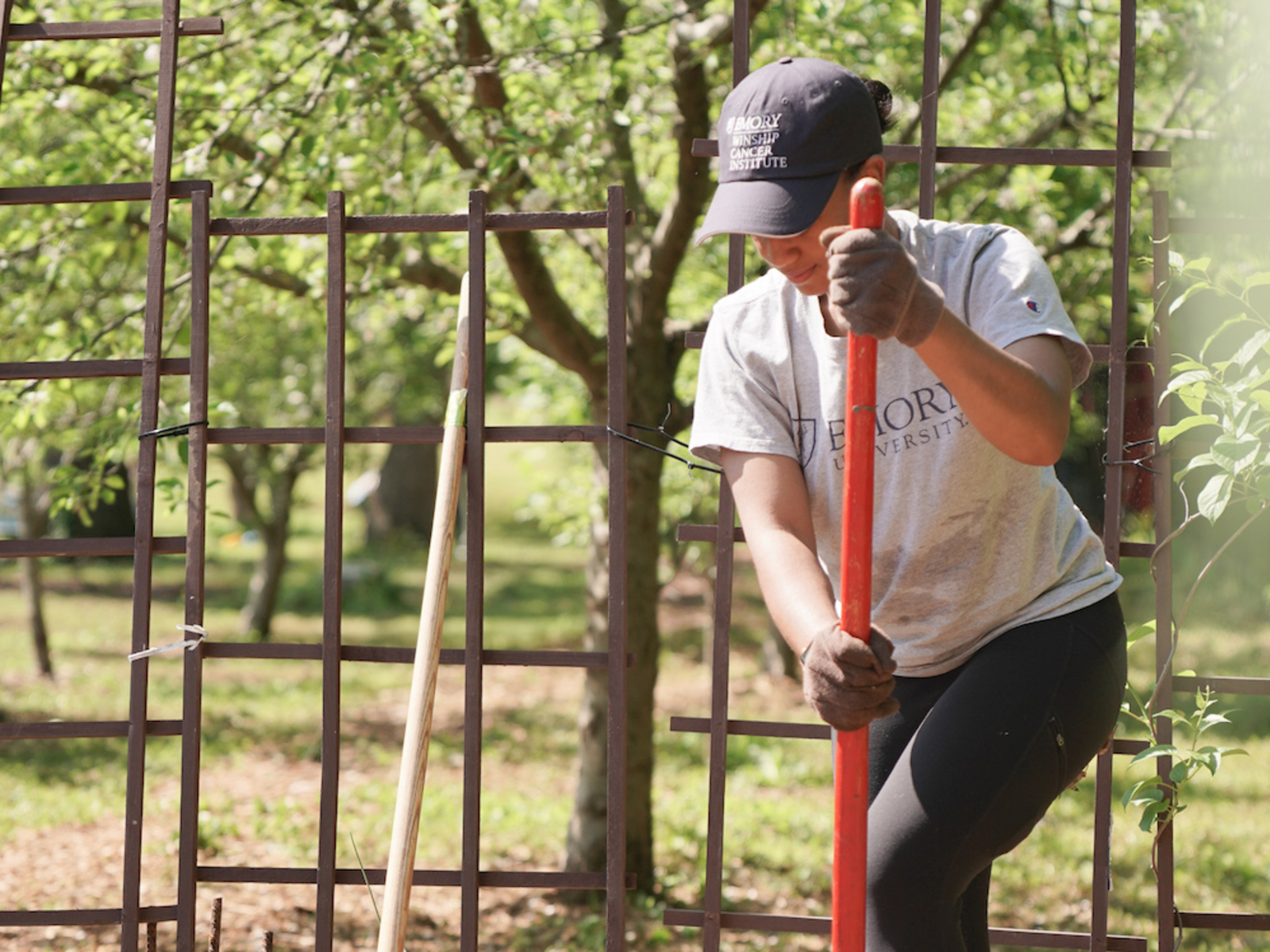 Volunteer tending a garden by using a shovel to holes to plant crops.